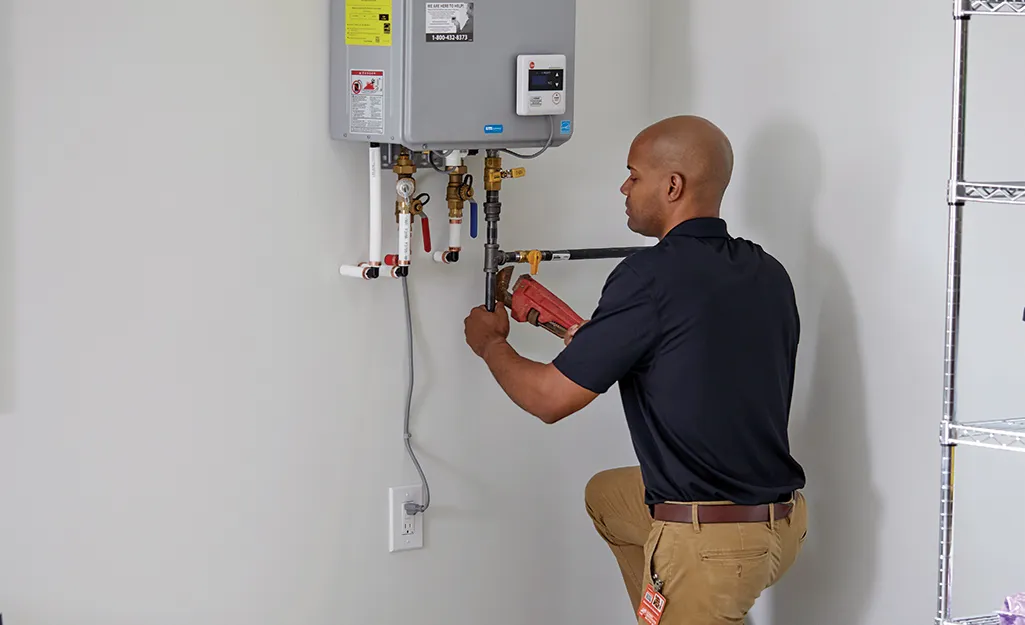 Man replaces tankless water heater in a garage.
