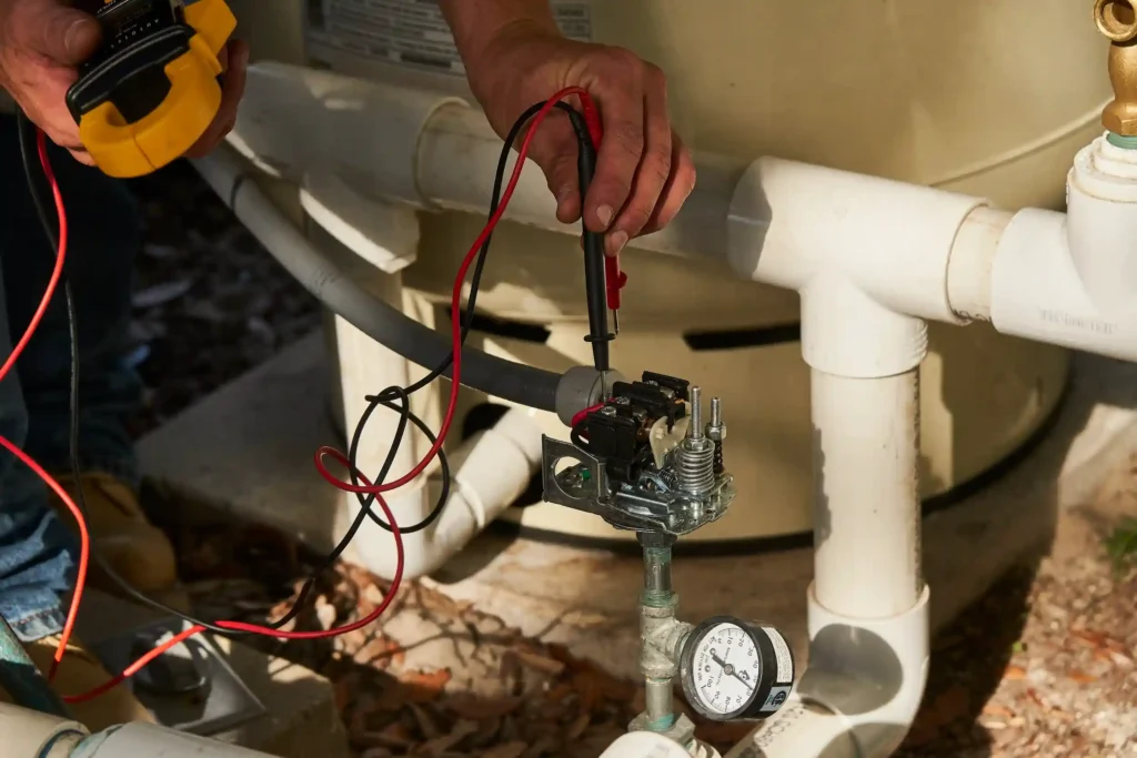 Technician testing electrical connections on a water heater.